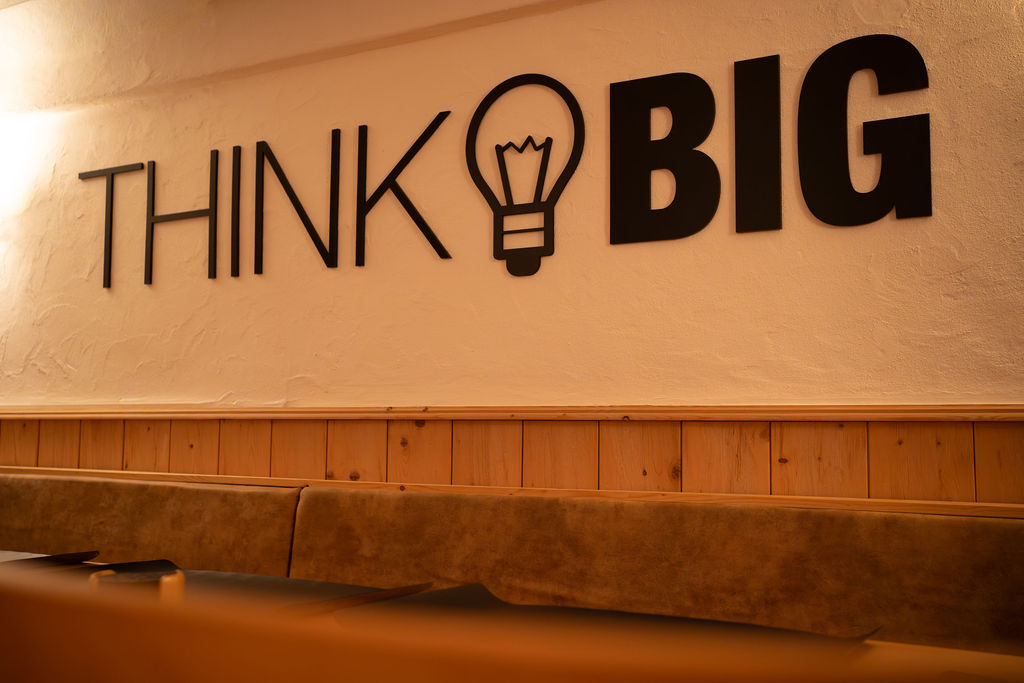 Wandbeschriftung mit den Worten "THINK BIG" und einer Glühbirne.